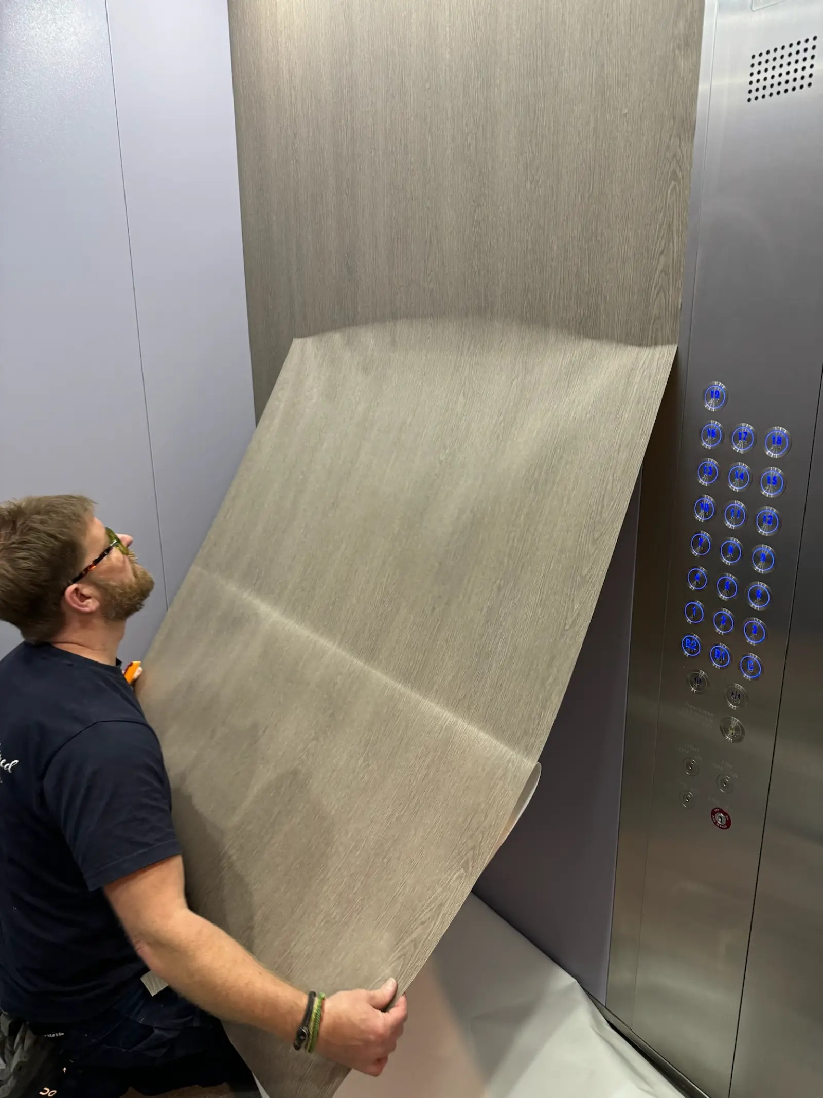 Installer applying architectural vinyl wrap to an elevator cab